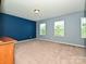 Spacious bedroom featuring natural light, carpeted flooring, and blue accent wall at 9027 Gray Willow Rd, Charlotte, NC 28227