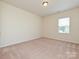 An empty bedroom with beige carpet, white walls, and natural light from the window at 9027 Gray Willow Rd, Charlotte, NC 28227