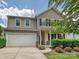 Tan two-story home with a two-car garage, and well-maintained landscaping at 9027 Gray Willow Rd, Charlotte, NC 28227