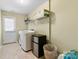 Bright laundry room with washer, dryer, mini fridge, and storage shelves at 9775 Mallard Glen Dr, Charlotte, NC 28262