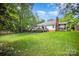 Large, green backyard showcasing the home's exterior, deck, and mature trees providing shade and privacy at 1014 Covewood Ct, Charlotte, NC 28270