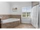 Tiled bathroom features a garden tub, window and separate shower at 1016 Spanish Moss Rd, Indian Trail, NC 28079