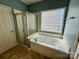 Bathroom featuring a soaking tub, a separate glass enclosed shower, and an eye-catching glass block window at 1043 Cambrook Ct, Concord, NC 28027