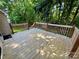 A wooden deck with wooden railings surrounded by green trees and shrubbery at 1043 Cambrook Ct, Concord, NC 28027