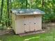 Outdoor storage shed with double doors and a metal roof, surrounded by trees and greenery at 1043 Cambrook Ct, Concord, NC 28027