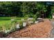 Backyard garden bed featuring various flowers and plants in a mulched landscape with a treehouse in the background at 10743 Ola Dr, Indian Land, SC 29707
