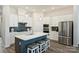Bright modern kitchen with white cabinetry, stainless steel appliances, and a large blue kitchen island with barstool seating at 1133 Idyllic Ln, Waxhaw, NC 28173