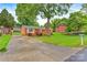 Charming brick home with a red door, landscaped yard, long concrete driveway, and mature trees at 1405 8Th Nw Ave, Conover, NC 28613