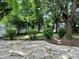 View of the landscaped backyard with a stone patio and lush greenery at 14211 Harlequin Dr, Charlotte, NC 28273