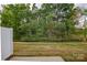 View of the backyard with lawn and treeline, enclosed with a white fence for privacy at 14806 Tamarack Dr, Charlotte, NC 28278