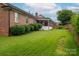 Backyard view showcases brick home with enclosed porch and lush, green lawn with manicured bushes at 1909 Wexford Ct, Gastonia, NC 28054
