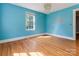 Bright bedroom with hardwood floors, large windows, and vibrant blue walls at 204 Blanche Ave, Belmont, NC 28012