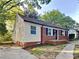 Charming single-story home featuring a brick foundation, light yellow siding, and mature trees in a well-maintained neighborhood at 2214 Grimes St, Charlotte, NC 28206