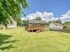 Large backyard featuring lush green grass, a wooden deck, and mature trees at 2927 Dubberly Ct, Matthews, NC 28105