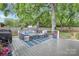 Back deck features gray seating, outdoor grill, and is covered with mature trees at 3809 Topsfield Rd, Charlotte, NC 28211