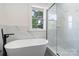 Well-lit bathroom featuring a freestanding tub, glass-enclosed shower, and marble tile at 418 Link St, Fort Mill, SC 29715