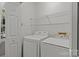 Bright laundry room with white washer and dryer, shelving, and a door with a window to the outside at 4232 Saint Audrey Pl, Charlotte, NC 28269