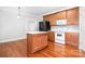 Cozy kitchen featuring wood cabinets, an island, white appliances, and hardwood floors at 4504 Sages Ave, Indian Trail, NC 28079