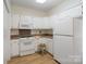 Kitchen area featuring a white refrigerator and microwave, laminate flooring and white cabinets at 608 Camrose Ne Cir, Concord, NC 28025