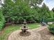 Landscaped backyard featuring a stone fountain, manicured lawn, patio seating, and privacy hedges at 6128 Fletcher Cir, Charlotte, NC 28226