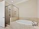 Bright bathroom showcasing a soaking tub with tile surround and a glass-enclosed shower at 6128 Fletcher Cir, Charlotte, NC 28226