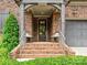 Inviting front porch with brick steps, seating and a dark front door with glass panes at 6128 Fletcher Cir, Charlotte, NC 28226