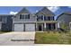 Charming two-story home with a well-manicured lawn, a two car garage and stone and gray toned siding at 127 Asmodean Ln, Troutman, NC 28166