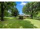 Lush backyard featuring mature trees and a covered storage structure at 128 Wandering Ln, Bessemer City, NC 28016