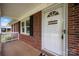 Close-up of the front door with brick siding and a white framed storm door at 128 Wandering Ln, Bessemer City, NC 28016