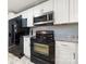 Modern kitchen features black appliances, granite countertops, and sleek white cabinetry at 128 Wandering Ln, Bessemer City, NC 28016