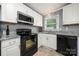 Well-lit kitchen featuring white cabinets, black appliances, stainless steel sink, and granite countertops at 128 Wandering Ln, Bessemer City, NC 28016