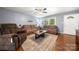 Comfortable living room with hardwood floors, brown sofa, and accent rug near the front door and window at 128 Wandering Ln, Bessemer City, NC 28016