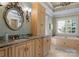 Elegant bathroom featuring a large vanity, jacuzzi tub, and decorative light fixtures at 13837 Grand Palisades Pkwy, Charlotte, NC 28278