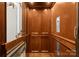 Spacious wooden elevator featuring wooden trim and handrail and detailed wood paneled doors at 13837 Grand Palisades Pkwy, Charlotte, NC 28278
