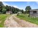 Gravel driveway leading to outbuildings surrounded by lush greenery and mature trees at 151 Lillyfield Dr, Rockwell, NC 28138