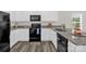 This kitchen offers black appliances, granite countertops, white cabinets, and luxury vinyl plank flooring at 155 Trail Wood Ct, Salisbury, NC 28146