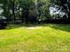 Grassy backyard features a concrete slab, trees and partial privacy fence, great for relaxation and entertaining at 20016 Walter Henderson Rd, Cornelius, NC 28031