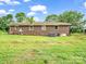 Rear view of a brick house with a grassy backyard and a few trees at 202 College Ave, Shelby, NC 28152