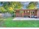 Backyard with covered patio, green lawn and tree-lined wooden fence at 3951 Whitehall Dr, Charlotte, NC 28208