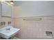 Bathroom featuring a vintage style sink, classic tile, and mirrored wall cabinet at 3951 Whitehall Dr, Charlotte, NC 28208