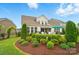Landscaped backyard featuring a patio, well-maintained lawn, trimmed evergreens, and garden beds at 4527 Waylon Ave, Fort Mill, SC 29715