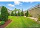 Expansive backyard with a retaining wall, well-maintained lawn, and a variety of mature trees at 4527 Waylon Ave, Fort Mill, SC 29715
