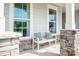 Cozy front porch seating area with decorative pillows and stone pillars at 5107 Raging Creek Dr, Indian Trail, NC 28079