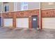 This image displays a three-car garage in a brick building, complete with white doors and a gray entryway at 511 Donatello Ave, Charlotte, NC 28205