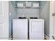 Well-lit laundry room showcases a white washer and dryer set with overhead wire shelving for storage at 5666 Stafford Rd # 9, Charlotte, NC 28054