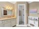 Well-lit bathroom with white cabinets, granite countertops, decorative mirror, and a glass enclosed shower with tile accents at 6132 Sharon Rd, Charlotte, NC 28210