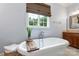 Soaking tub with wood caddy and a plant near bright window and vanity at 6132 Sharon Rd, Charlotte, NC 28210