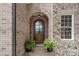 Charming arched front door with stone and brick surround, flanked by potted ferns at 6132 Sharon Rd, Charlotte, NC 28210