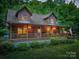 Charming log cabin with inviting covered porch and an American flag, nestled in a lush green setting at 95 Odell Ct, Taylorsville, NC 28681