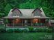 Charming log home with a covered front porch, lush landscaping, and American flag at 95 Odell Ct, Taylorsville, NC 28681